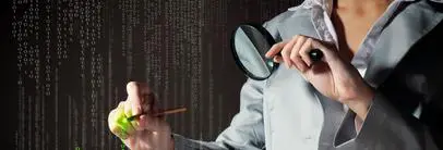 A man holding a magnifying glass and writing on paper.