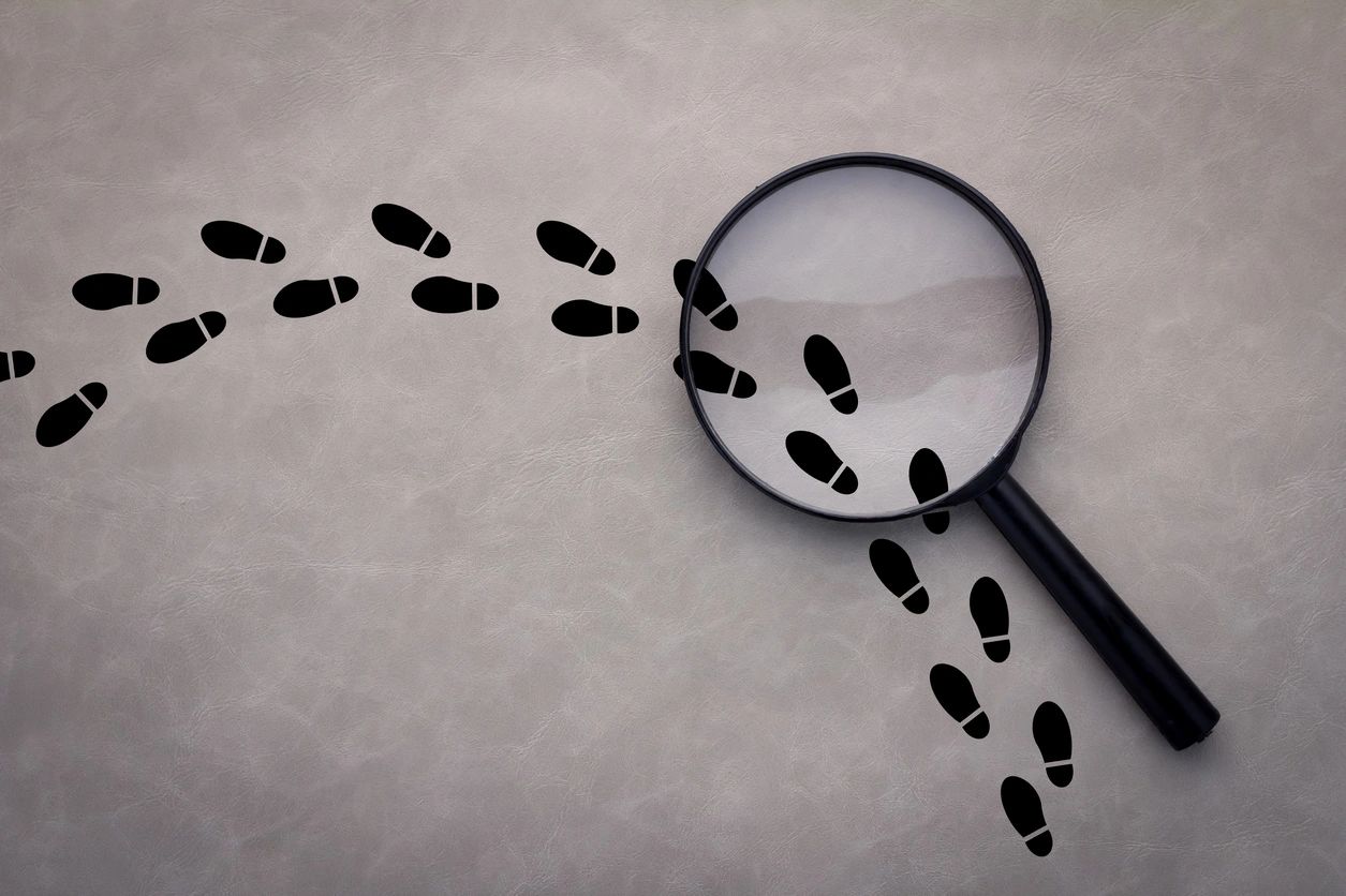 A magnifying glass and footprints on paper